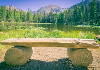 Bench in front of Nymph Lake at Rocky Mountain National Park on a sunny day with Longs Peak behind the lake